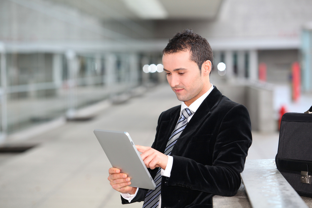 Salesman stannnding oustide with electronic tablet